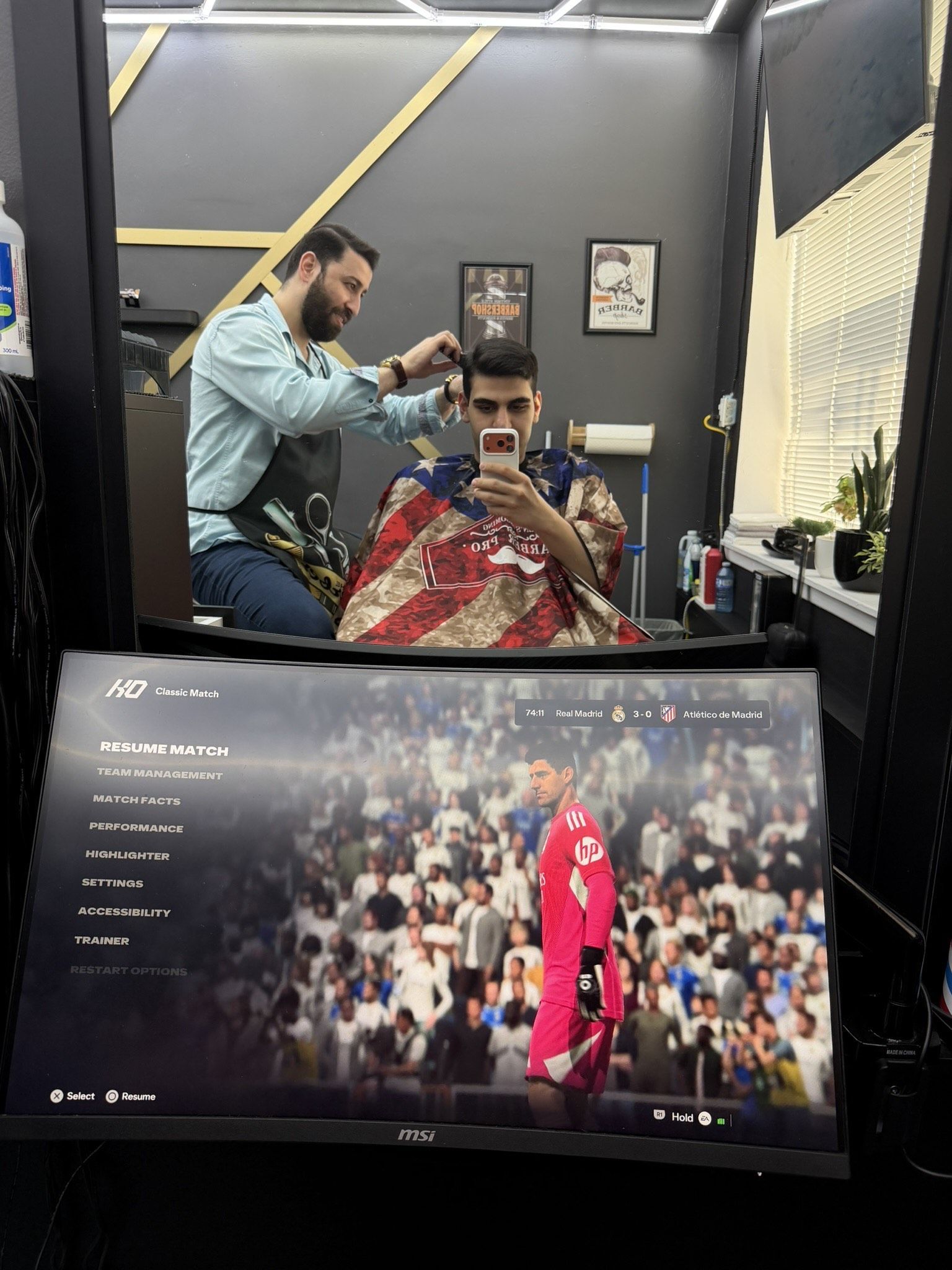 Client getting a haircut with a football game on the curved screen in front of the chair